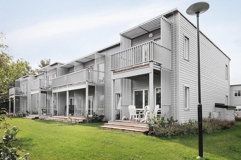 Fasadbild som visar baksidan av radhusen i Bjuv med ljusgrå träfasad